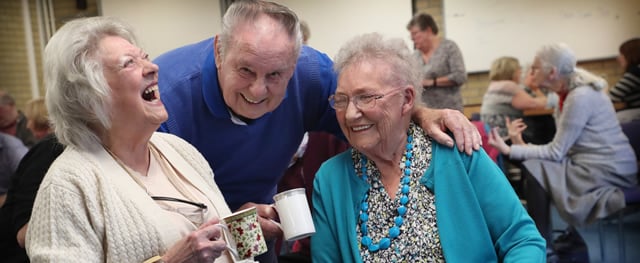 Group of people sharing a joke and cups of tea