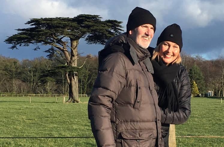 Kenny Young, heart attack survivor, stands alongside with Lorraine in a field with winter clothing on.