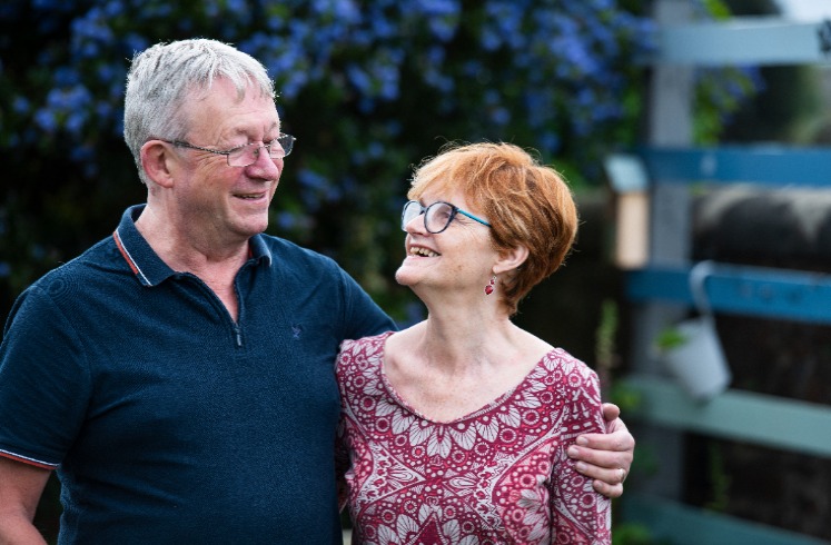 Nancy and her husband Kevin stand smiling