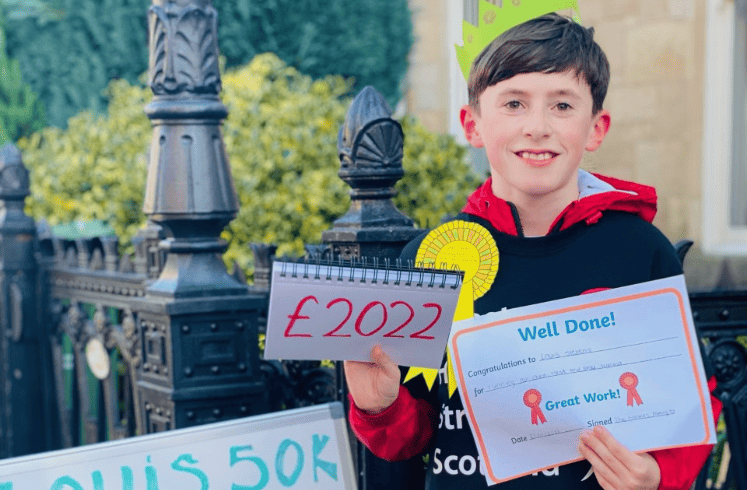 Louis is a young boy with short dark hair, posing with a certificate.